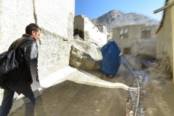 Going up the hill. The water pipe can be seen in a gulley. Zuhair's mother walks in front of Zek.
